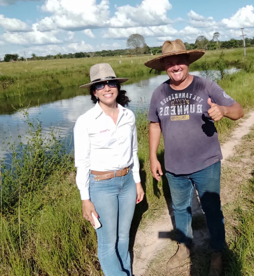Soraia e um produtor sorriem à beira de um viveiro, durante visita a uma propriedade